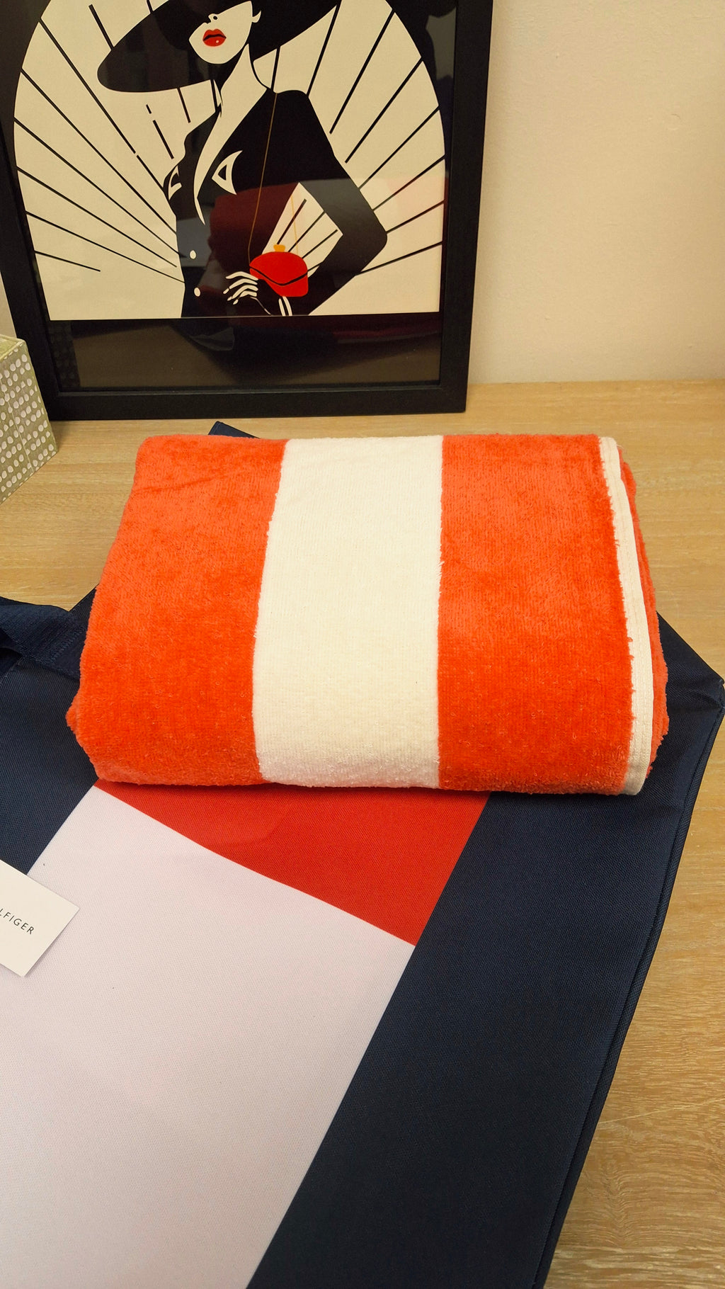 A folded red and white striped towel on top of the Tommy Hilfiger Beach Bag.