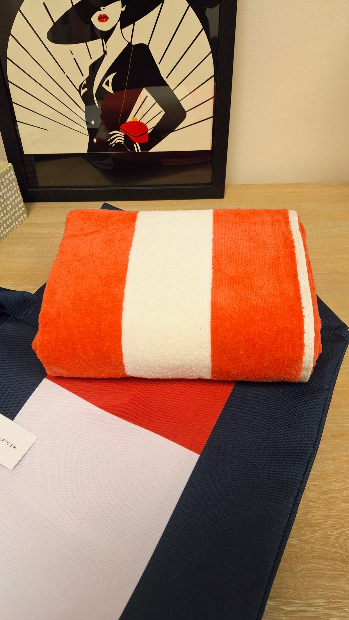 A folded red and white striped towel on top of the Tommy Hilfiger Beach Bag.