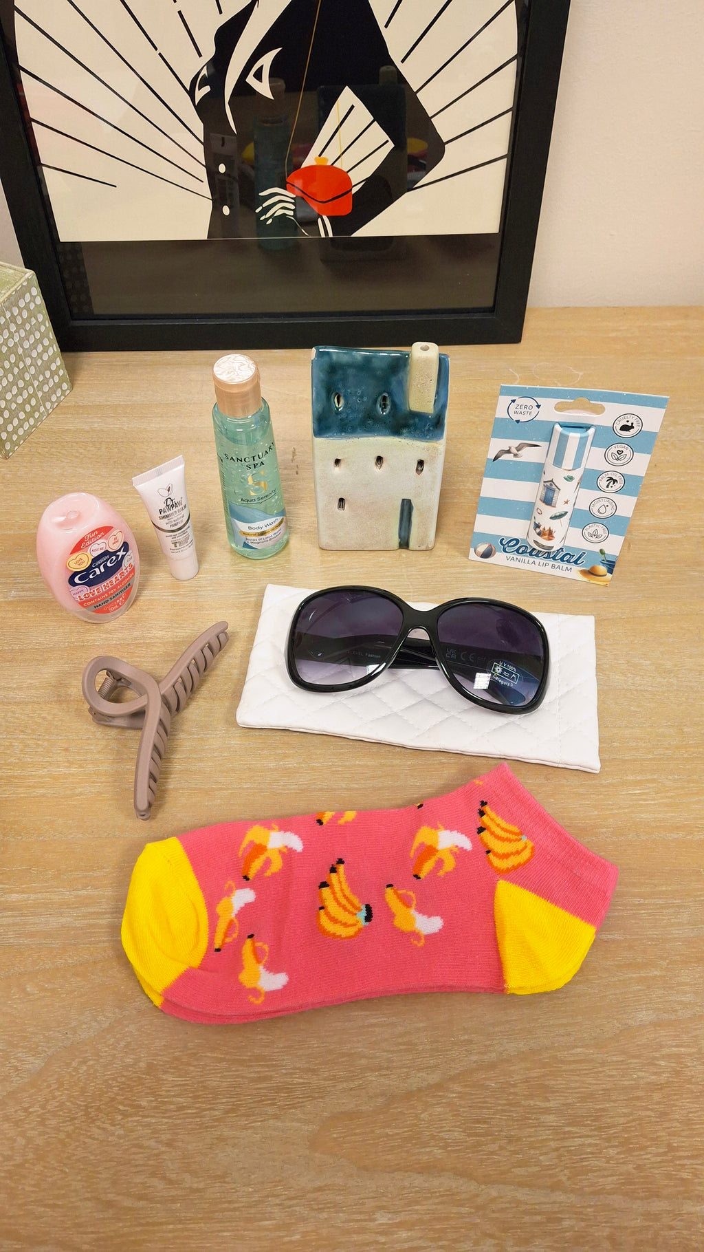 A styled flat-lay of trainer socks alongside other lifestyle accessories like sunglasses, a hair claw clip and toiletries.