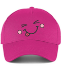 A bright pink baseball cap featuring a cartoon face embroidery on the front with winking eyes, pink cheeks, and a sticking-out tongue.
